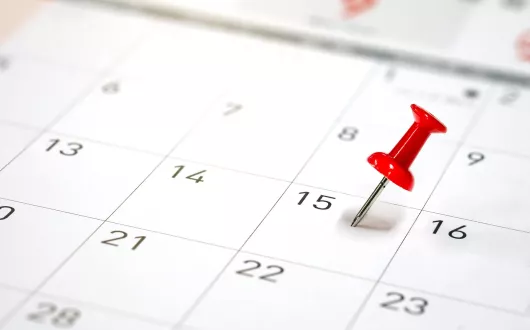 Zdjęcie kalendarza. Data zaznaczona czerwoną pinezką.