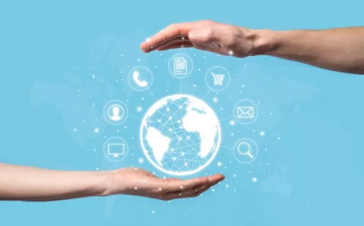 Widok dwóch dłoni trzymających koncepcję kuli ziemskiej otoczonej wirtualnymi ikonami.