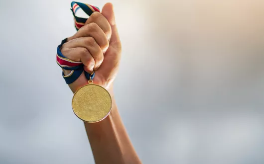 Ręka trzymająca złoty medal