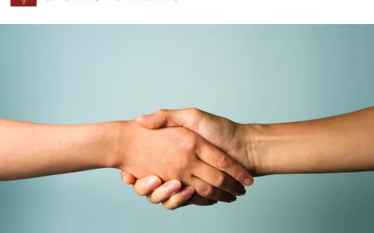 Dwie trzymające się ręce na niebieskim tle.