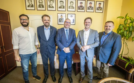 czterech panów stoi na tle zdjęć i ściany
