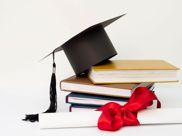 Widok czapki akademickiej z książkami i dyplomem