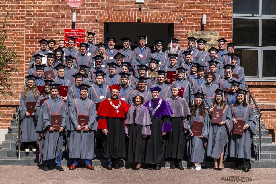 Absolwenci w togach stojący na schodach Instytutu Fizyki