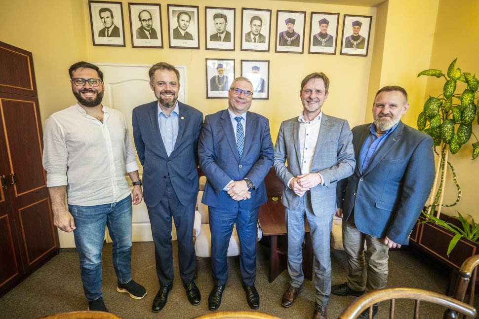 czterech panów stoi na tle zdjęć i ściany