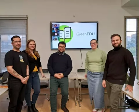 Partnerzy projektu pozują w laboratorium na tle dużego ekranu
