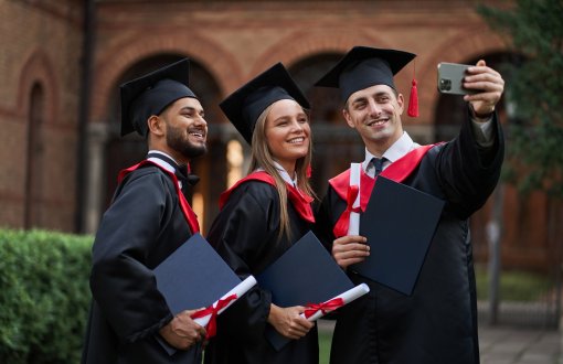 Grupa uśmiechniętych absolwentów robi sobie selfie