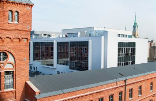 Instytut Fizyki: pofabryczny budynek z czerwonej cegły z wieżyczką. W tle biały nowoczesny budynek