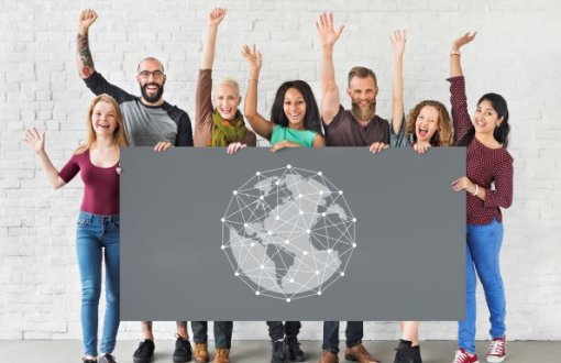 Międzynarodowa grupa radosnych studentów trzyma plakat z białym globusem na szarym tle