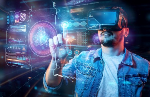 Futurystyczna koncepcja internetu i technologii multimedialnych: młody człowiek w wirtualnych okularach dotykający wykresów na wirtualnym interfejsie. 