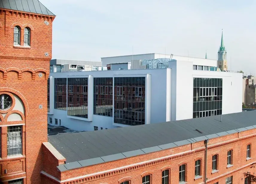 Instytut Fizyki: pofabryczny budynek z czerwonej cegły z wieżyczką. W tle biały nowoczesny budynek